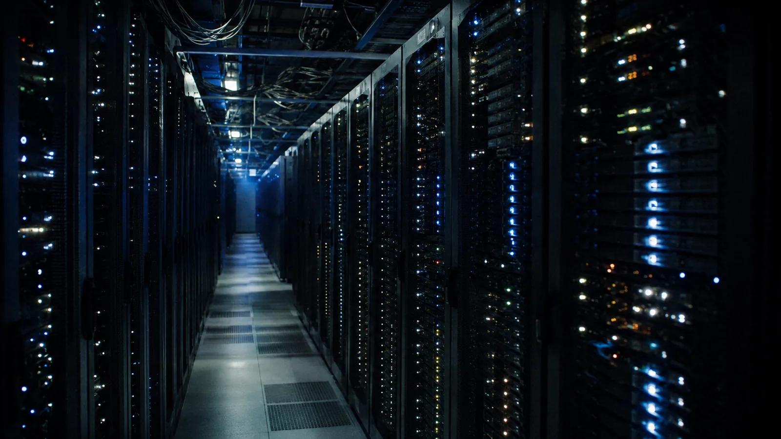 A data center aisle at night, endless racks of tiny status lights
