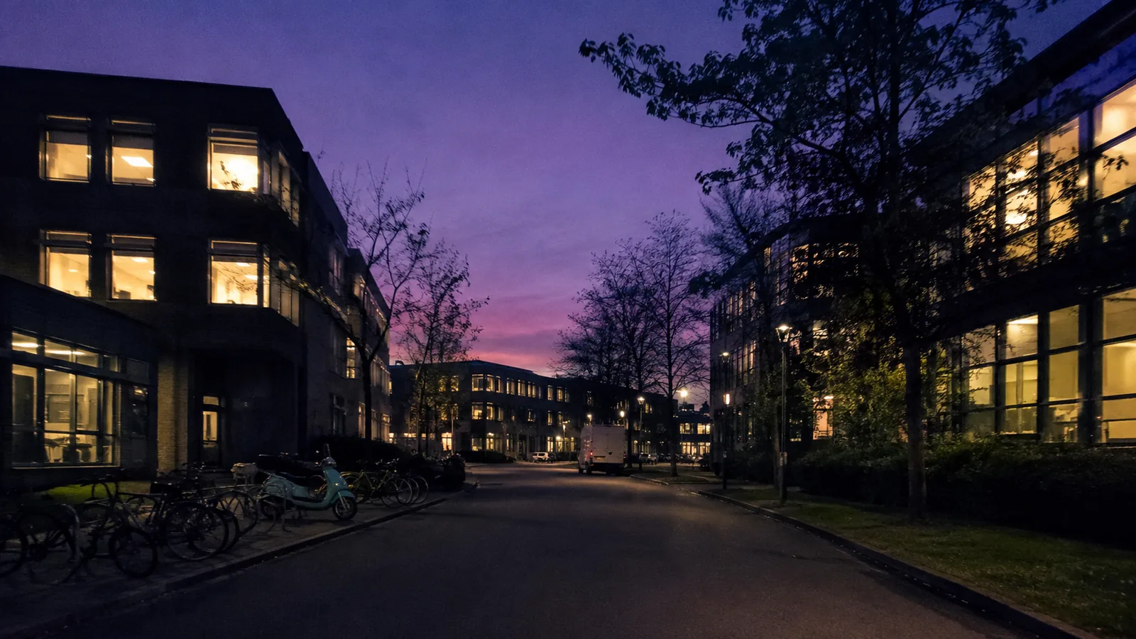 A small-business office park at dusk, many small windows lit