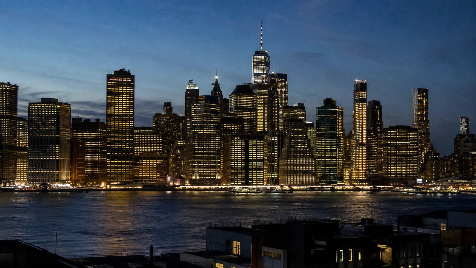 Manhattan at dusk — hundreds of lit windows over calm water